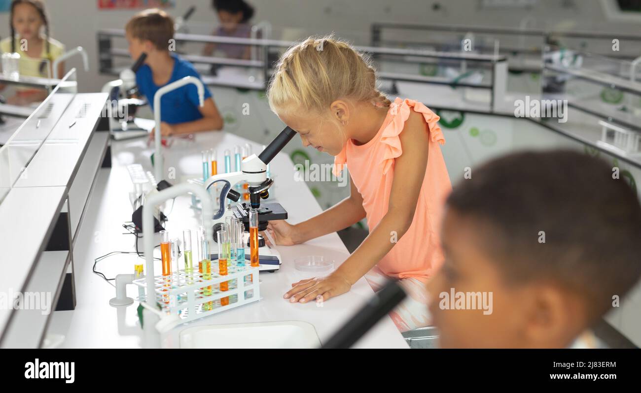 Multiracial elementary students looking through microscope during