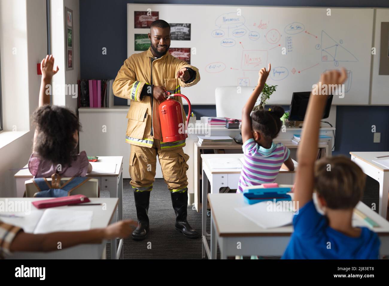 African american young male teacher pointing on multiracial elementary students in safely education Stock Photo