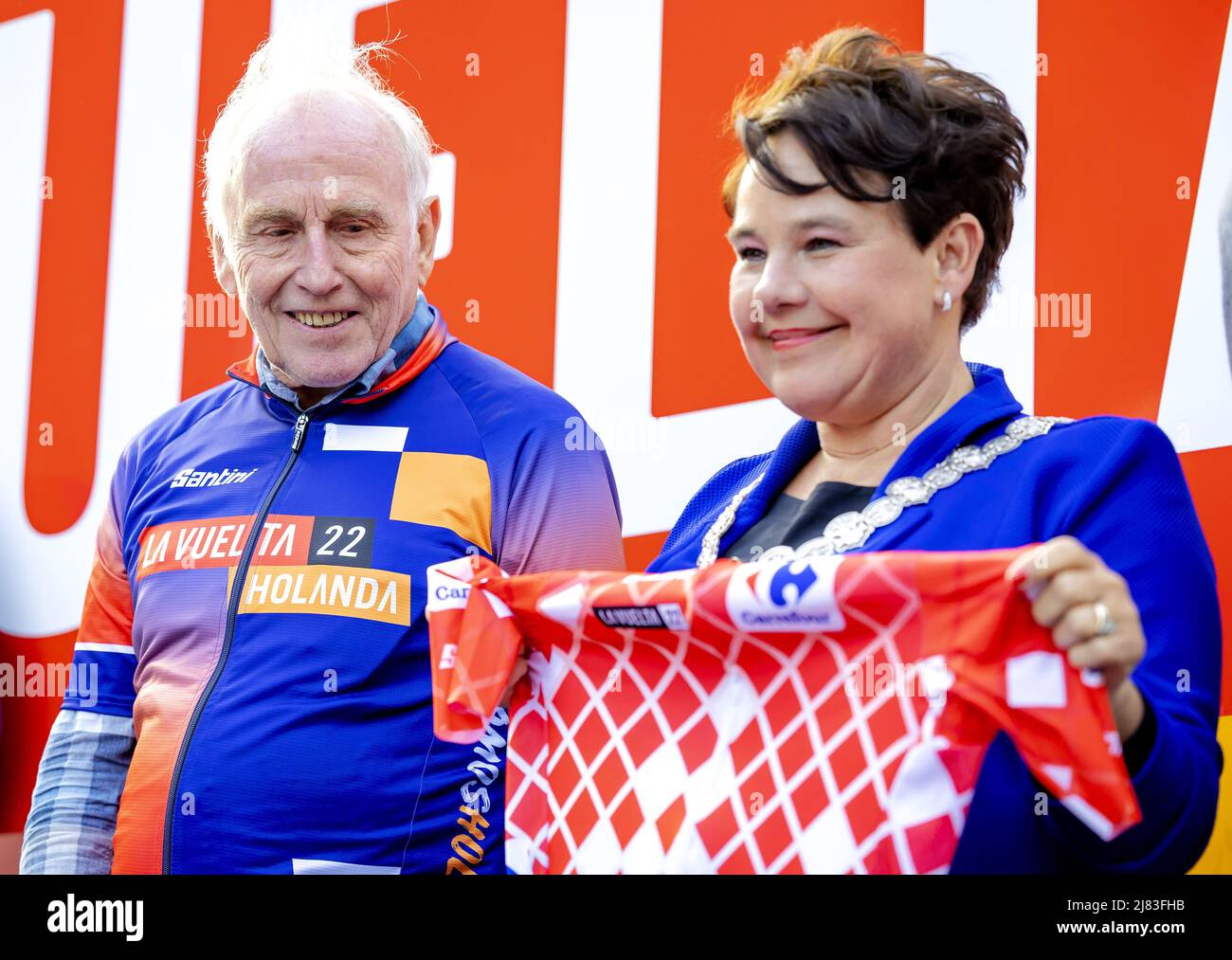 2022-05-12 19:26:52 UTRECHT - Joop Zoetemelk hands over the official red  Vuelta jersey to Mayor Sharon Dijksma on the Neude, during an event that  looks ahead to the cycling event The Tour