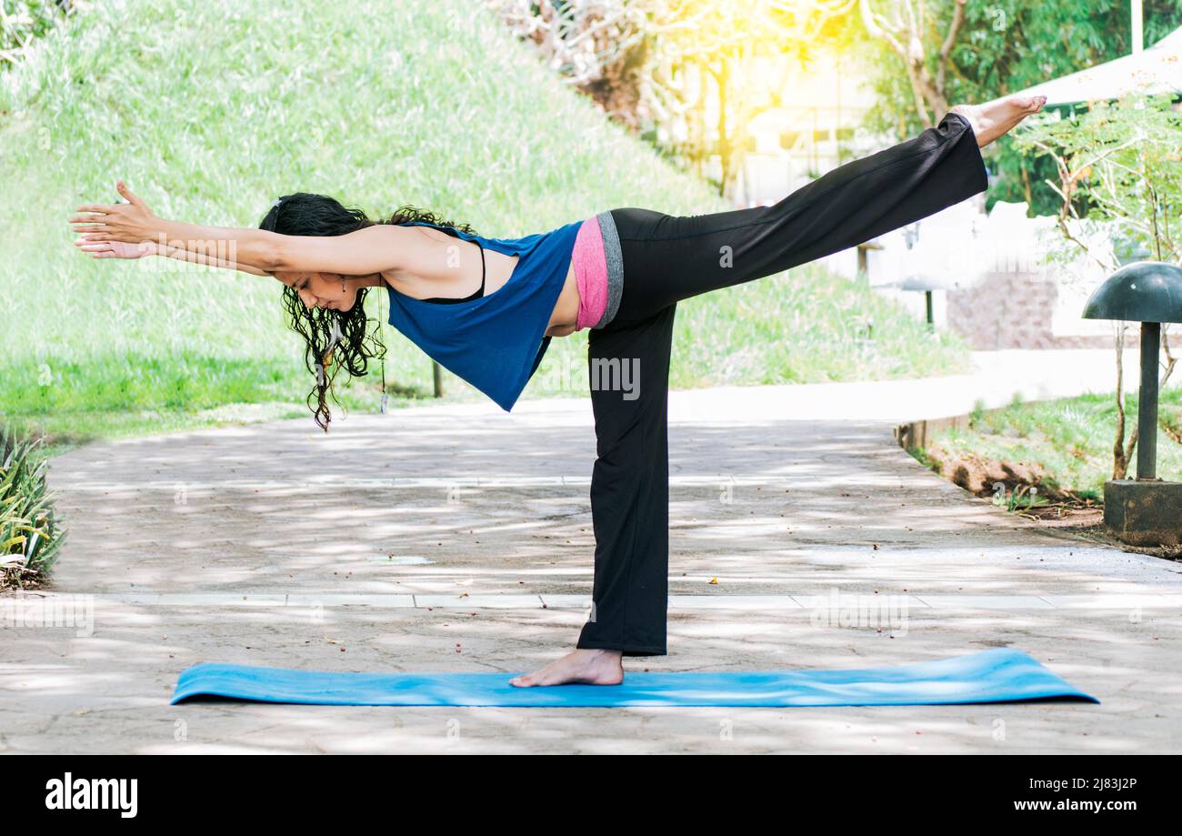 Woman doing warrior III yoga outdoors, girl doing Virabhadrana III yoga, young woman doing yoga outdoors, warrior III yoga concept Stock Photo