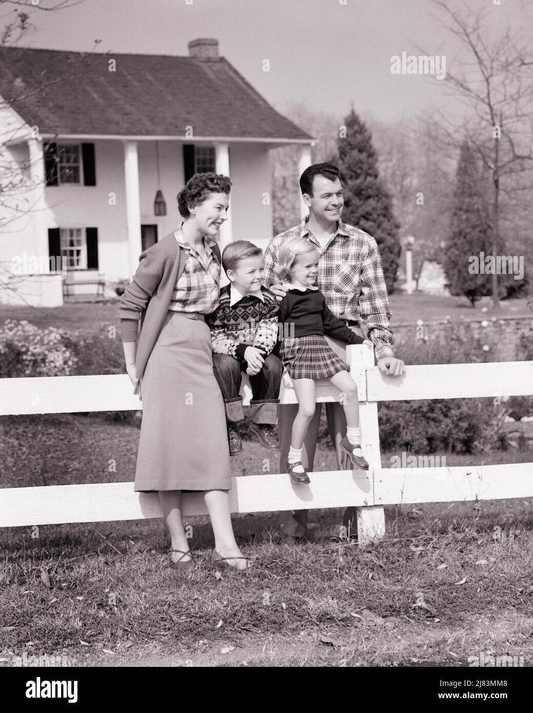1950s FAMILY OF 4 BY WHITE FENCE IN FRONT OF TWO STORY HOUSE WITH COLUMNS BOY AND GIRL SITTING ON FENCE PARENTS STANDING - j3184 HAR001 HARS STORY NOSTALGIC PAIR 4 SUBURBAN SPRING MOTHERS OLD TIME NOSTALGIA BROTHER OLD FASHION SISTER JUVENILE STYLE WELCOME YOUNG ADULT ABSTRACT PLEASED FAMILIES JOY LIFESTYLE FEMALES HOUSES MARRIED BROTHERS SPOUSE HUSBANDS HEALTHINESS HOME LIFE COPY SPACE FRIENDSHIP FULL-LENGTH LADIES PERSONS RESIDENTIAL CARING MALES BUILDINGS SIBLINGS SISTERS FATHERS B&W PARTNER DREAMS HAPPINESS CHEERFUL AND DADS EXTERIOR PRIDE COLUMNS HOMES SIBLING SMILES CONNECTION JOYFUL Stock Photo