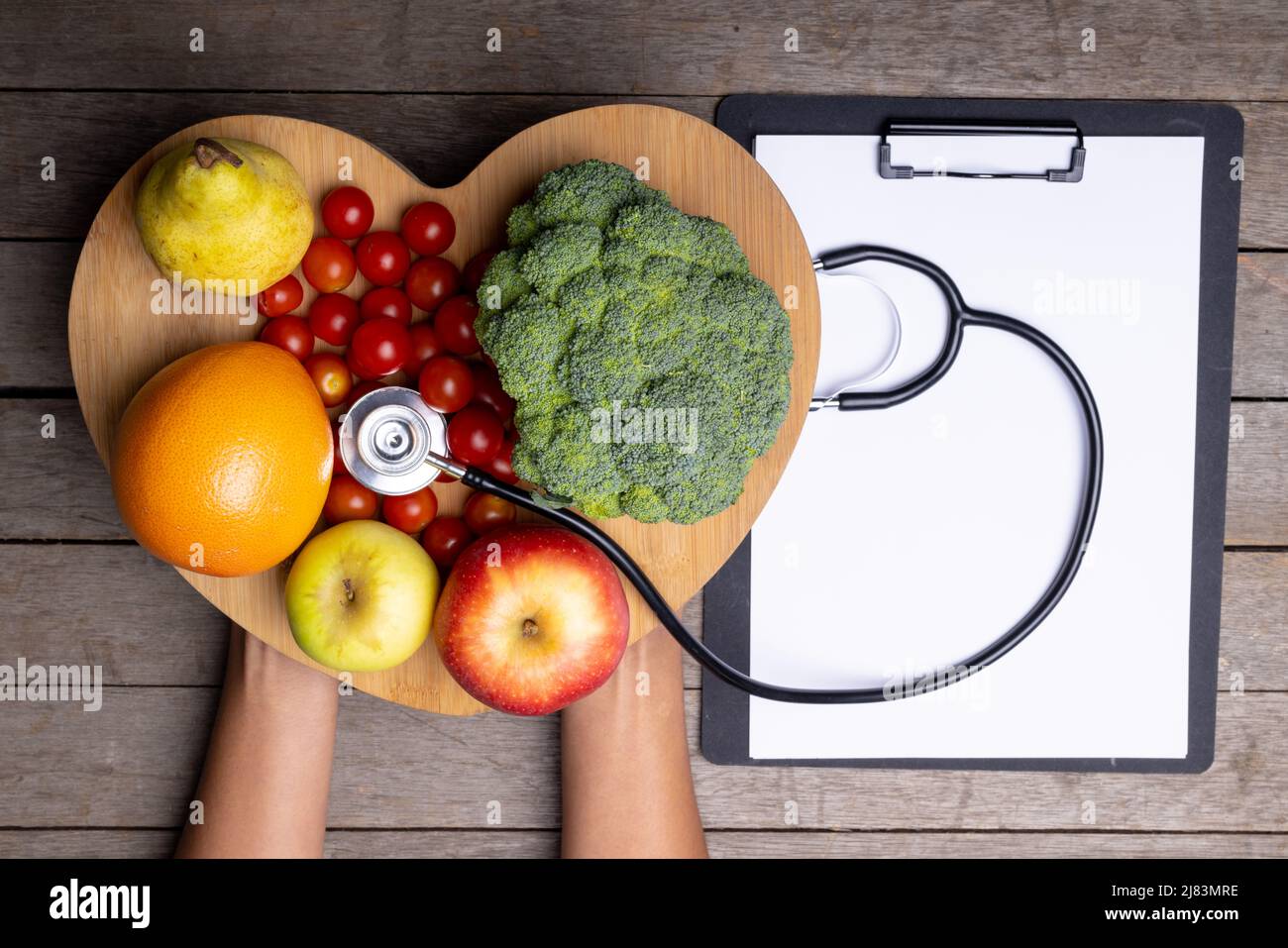 African american woman holding heart shape with vegetables, fruits, stethoscope by report on table Stock Photo