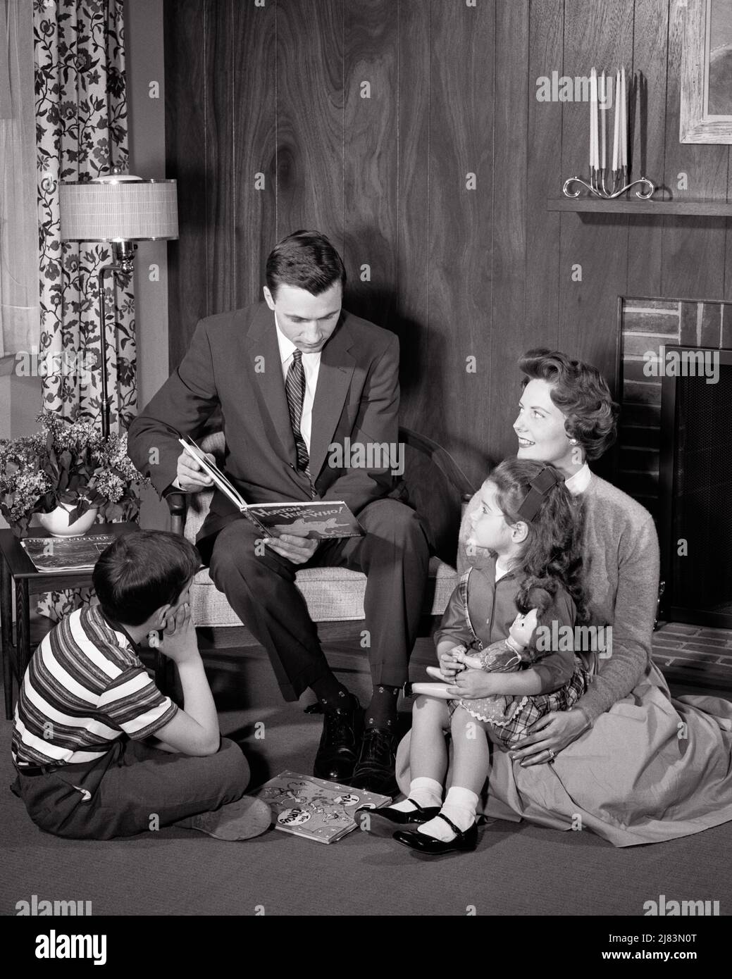 1950s FATHER SITTING IN CHAIR READING A DR SUESS STORY HORTON HEARS A WHO TO HIS SON DAUGHTER AND WIFE ALL SITTING ON FLOOR - j5013 HAR001 HARS INDOORS FLOOR NOSTALGIC PAIR 4 SUBURBAN MOTHERS OLD TIME NOSTALGIA BROTHER READ OLD FASHION SISTER JUVENILE STYLE COMMUNICATION TEAMWORK INFORMATION SONS FAMILIES JOY LIFESTYLE SATISFACTION FEMALES MARRIED BROTHERS SPOUSE HUSBANDS HOME LIFE COPY SPACE FRIENDSHIP HALF-LENGTH LADIES DAUGHTERS PERSONS MALES SIBLINGS SISTERS FATHERS B&W PARTNER SUIT AND TIE HAPPINESS HIS LIVING ROOM AND DADS DR KNOWLEDGE SIBLING WHO CONNECTION IMAGINATION GROWTH JUVENILES Stock Photo