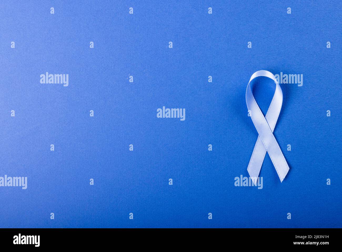 Directly above shot of stomach cancer awareness blue ribbon isolated against blue background Stock Photo