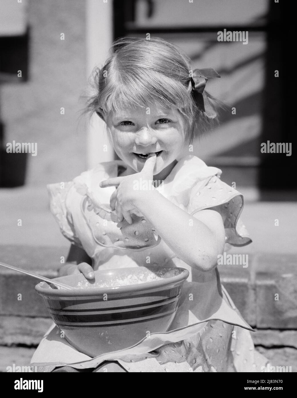 1930s SMILING LITTLE GIRL LOOKING AT CAMERA WITH BIG BOWL OF WHIPPED CREAM IN HER LAP LICKING HER FINGERS AND THUMB ON HER LIPS - j5915 HAR001 HARS WINNING THUMB HEALTHINESS HOME LIFE COPY SPACE HALF-LENGTH CHIN B&W LAP EYE CONTACT LICKING HAPPINESS CHEERFUL DISCOVERY AND IN ON SMILES JOYFUL PLEASANT AGREEABLE CHARMING JUVENILES LOVABLE PLEASING WHIPPED CREAM ADORABLE APPEALING BLACK AND WHITE CAUCASIAN ETHNICITY HAR001 OLD FASHIONED Stock Photo