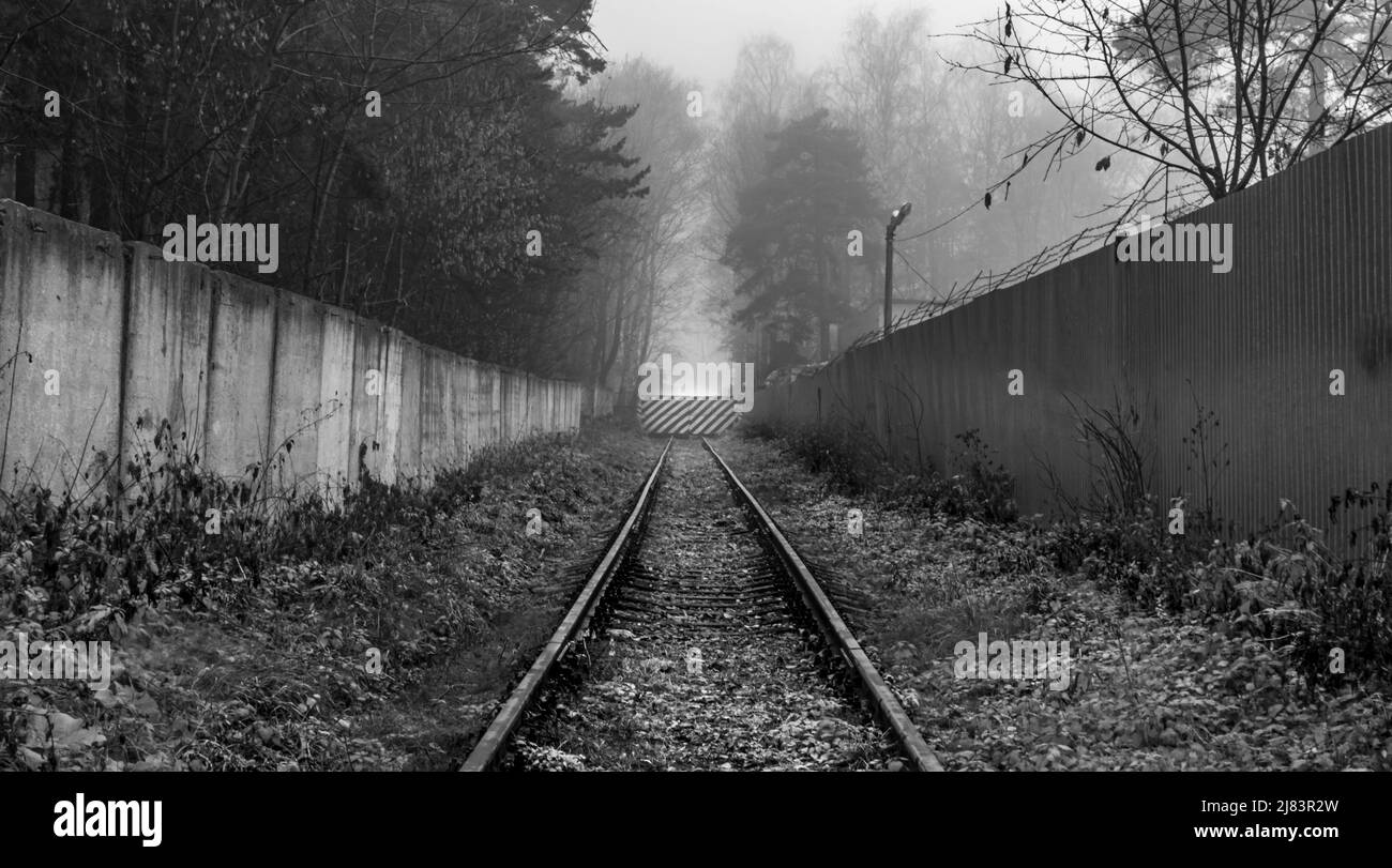 An old railway to a semi-abandoned closed facility in the autumn in the fog. Stock Photo