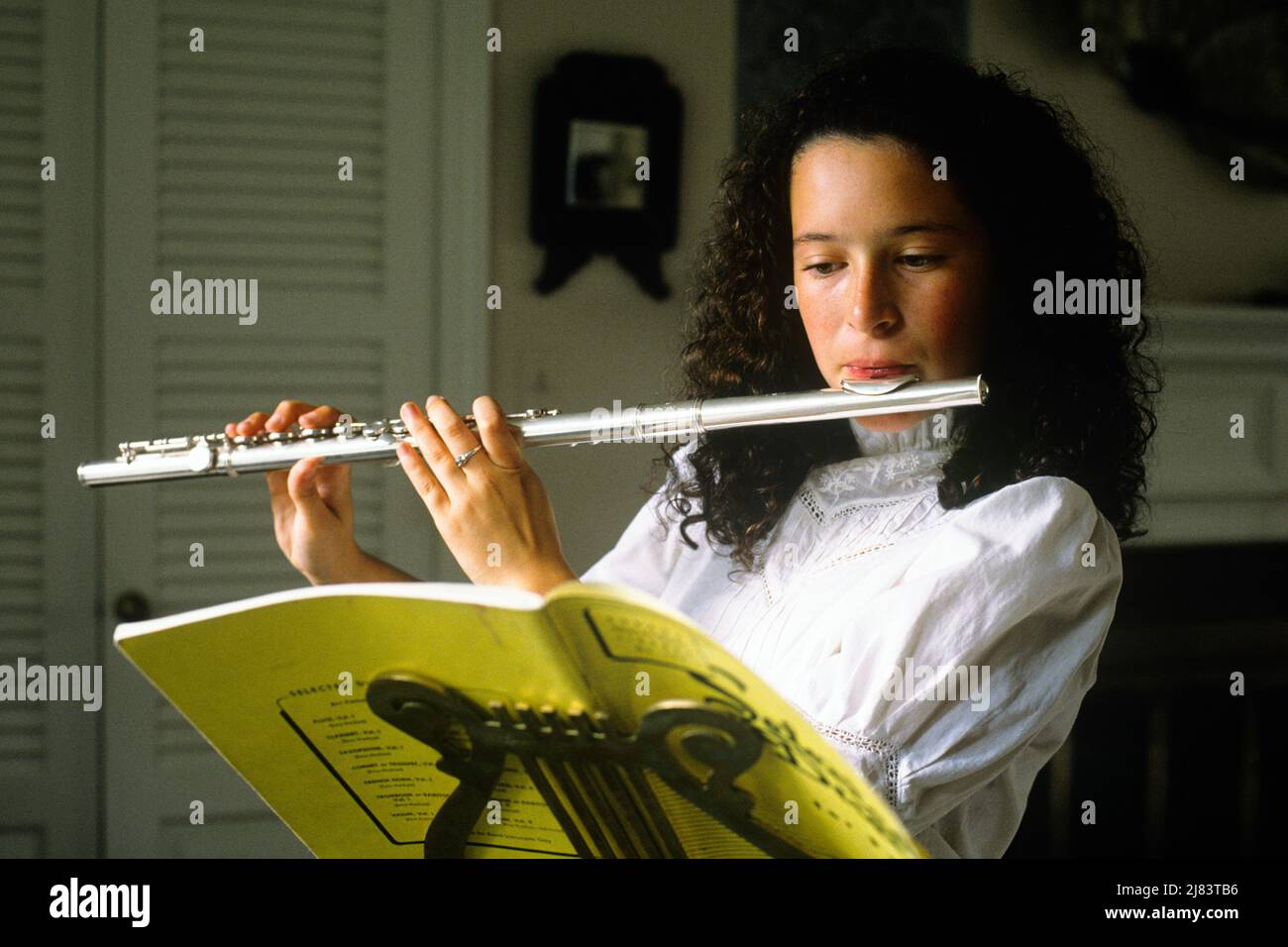 1980s BRUNETTE TEENAGE GIRL PLAYING A FLUTE READING SHEET MUSIC ON BRASS MUSIC STAND - km9833 NET002 HARS HOME LIFE COPY SPACE HALF-LENGTH PERSONS PRACTICE TEENAGE GIRL FLUTE BRASS CONFIDENCE BRUNETTE GOALS SCHOOLS PERFORMING ARTS SKILL PERFORMER PRIDE ENTERTAINER HIGH SCHOOL MUSICAL INSTRUMENT HIGH SCHOOLS CONNECTION TEENAGED ENTERTAINERS FLAUTIST GROWTH JUVENILES PERFORMERS CAUCASIAN ETHNICITY OLD FASHIONED WIND INSTRUMENT Stock Photo