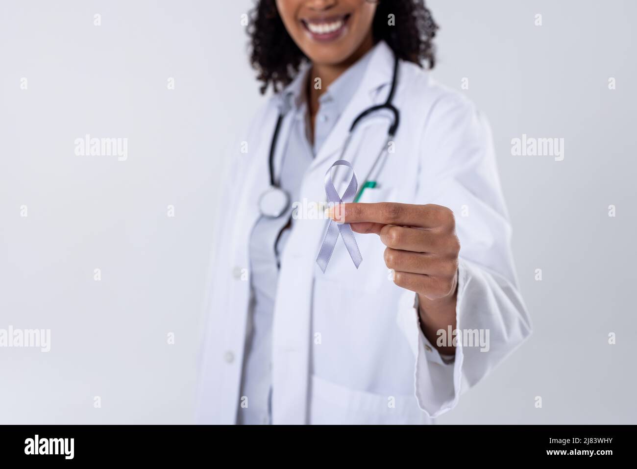 Midsection of happy african american mid adult female doctor with white lung cancer awareness ribbon Stock Photo
