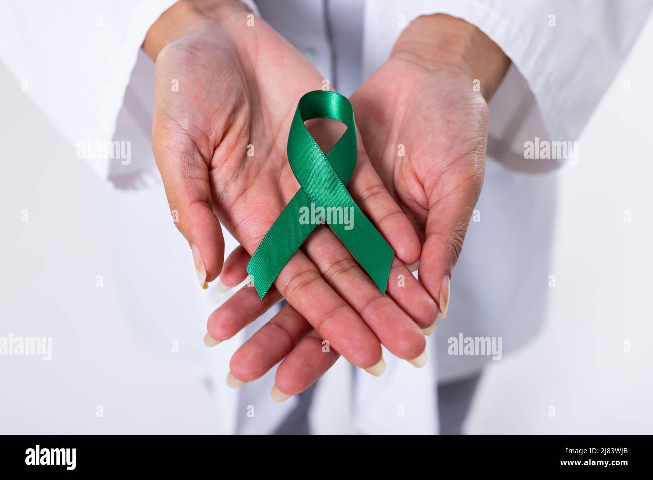 Midsection of african american mid adult female doctor with green mental health awareness ribbon Stock Photo
