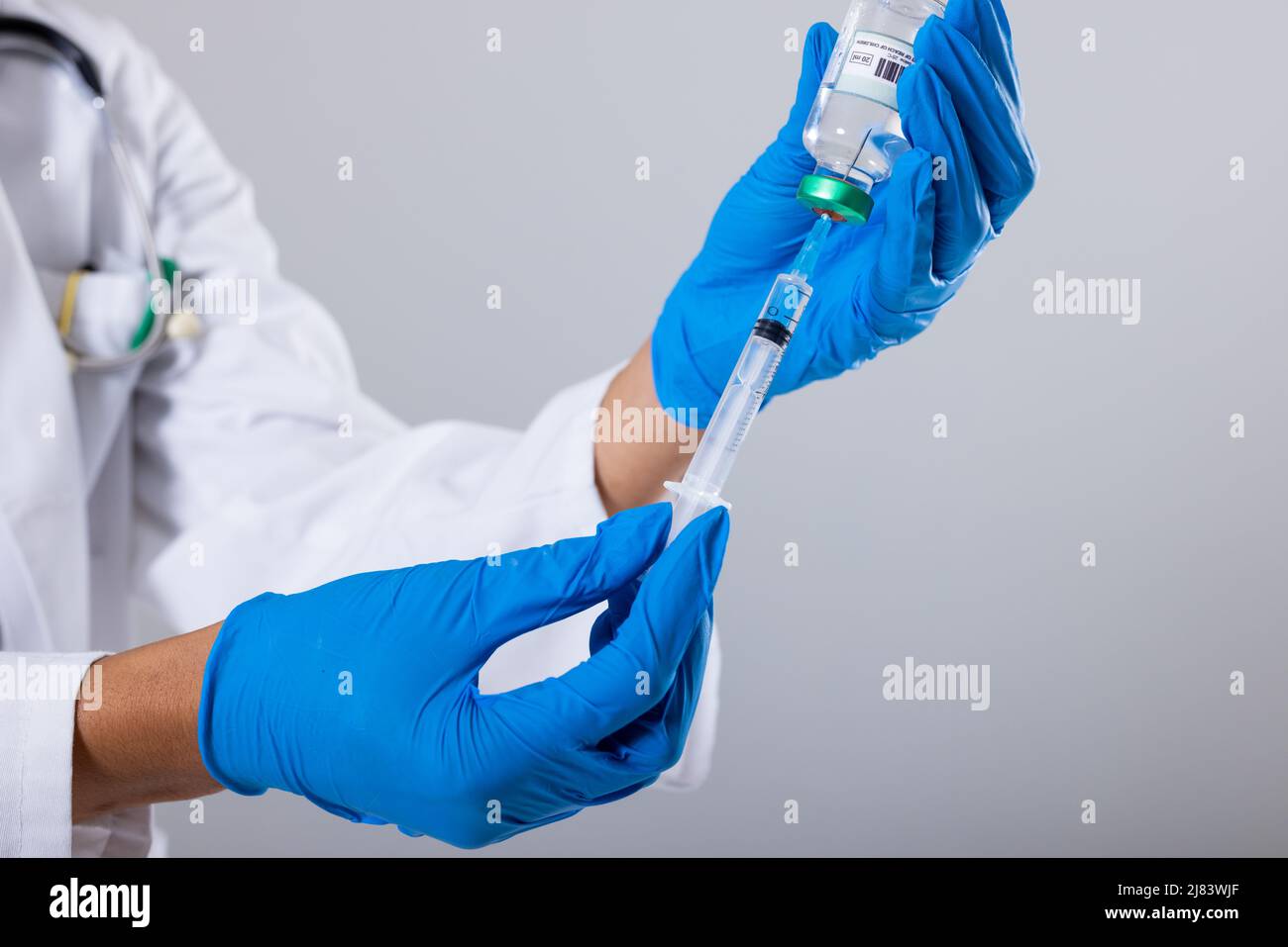 Midsection of african american mid adult female doctor wearing gloves holding vial and syringe Stock Photo