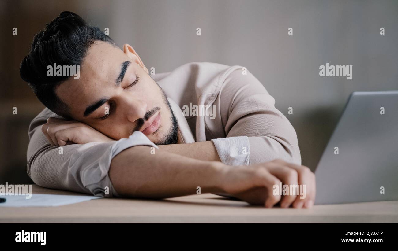Sleepy unproductive man office male worker businessman falling asleep at office desk tired multiracial student closed eyes feeling exhausted after Stock Photo