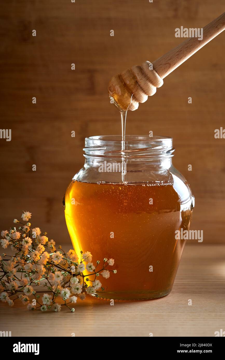 Fresh Honey in glass jar with dipper on wooden background Stock Photo