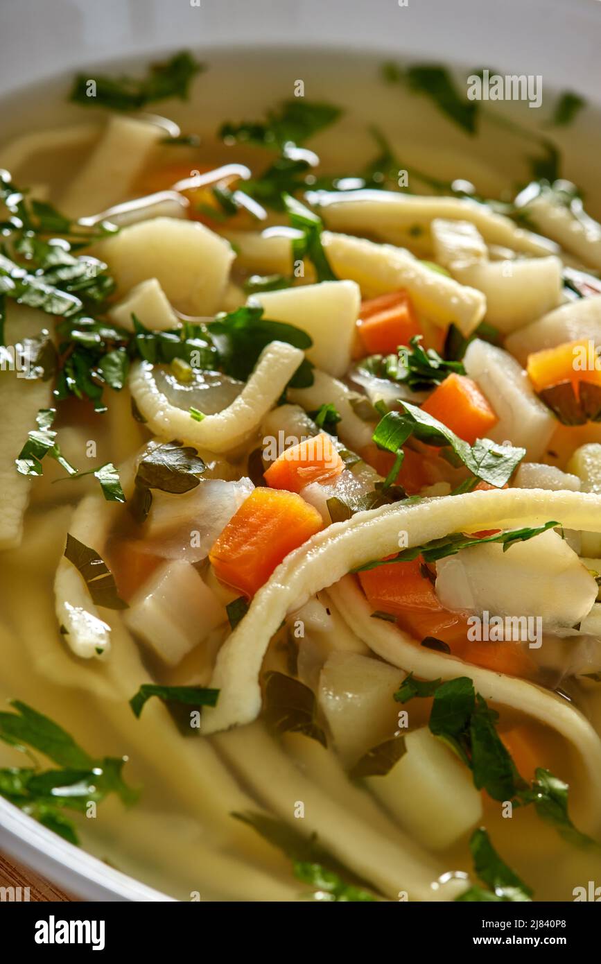 Warm vegetable soup with noodles and fresh chopped parsley - close up view Stock Photo