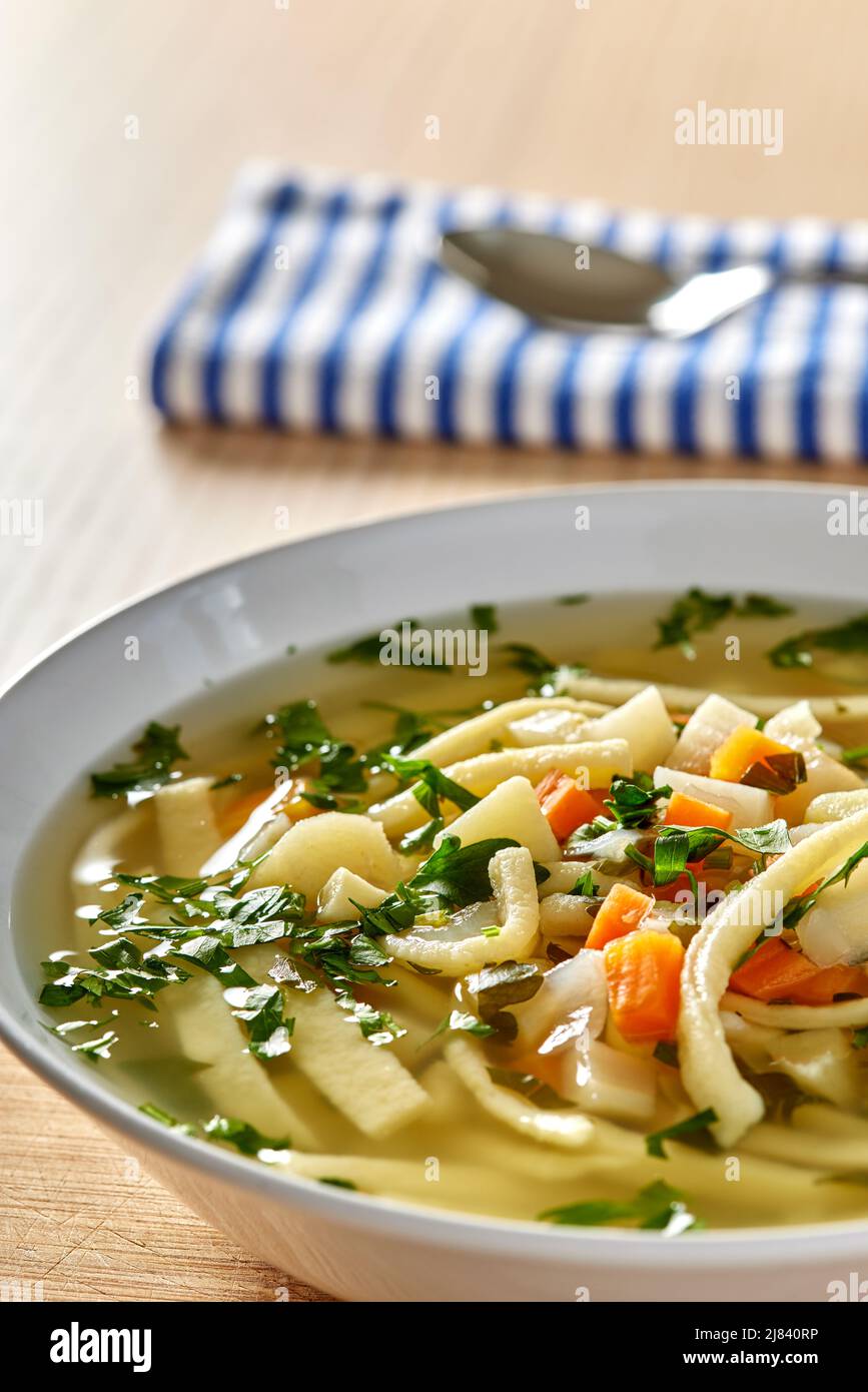 Warm vegetable soup with noodles and fresh chopped parsley - close up view Stock Photo