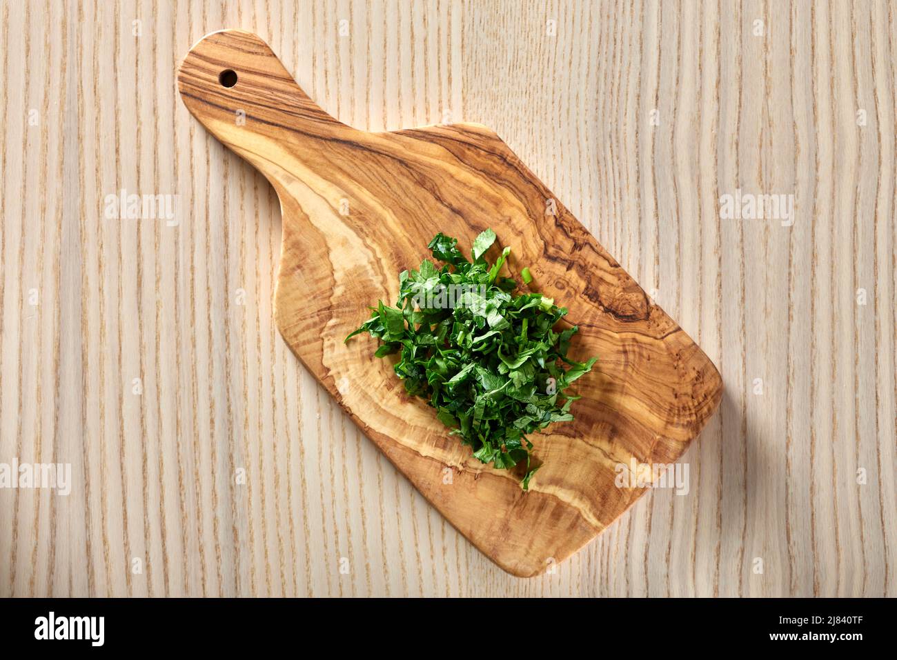 Chopped green parsley on a cutting board made from olive wood - top view Stock Photo