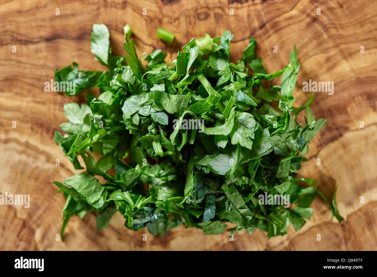 Chopped green parsley on a cutting board made from olive wood - close up view Stock Photo