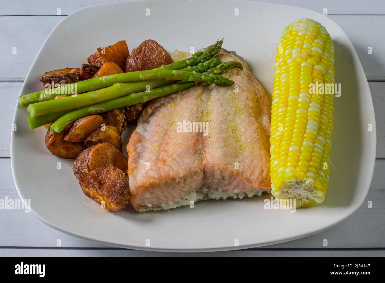 baked salmon served with corn , asparagus and red roasted potatoes