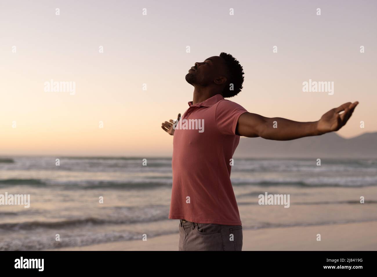 Side view of african american young man with arms outstretched standing ...