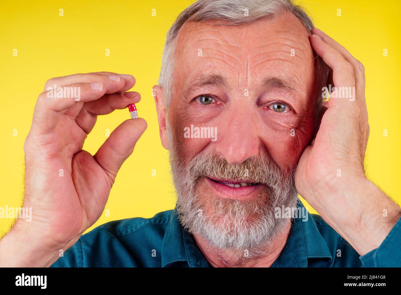 Happy old man holding vitamins studio yellow background Stock Photo