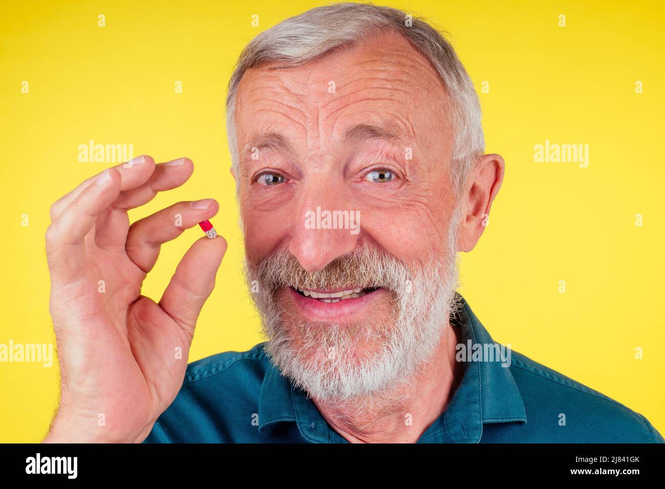 Happy old man holding vitamins studio yellow background Stock Photo