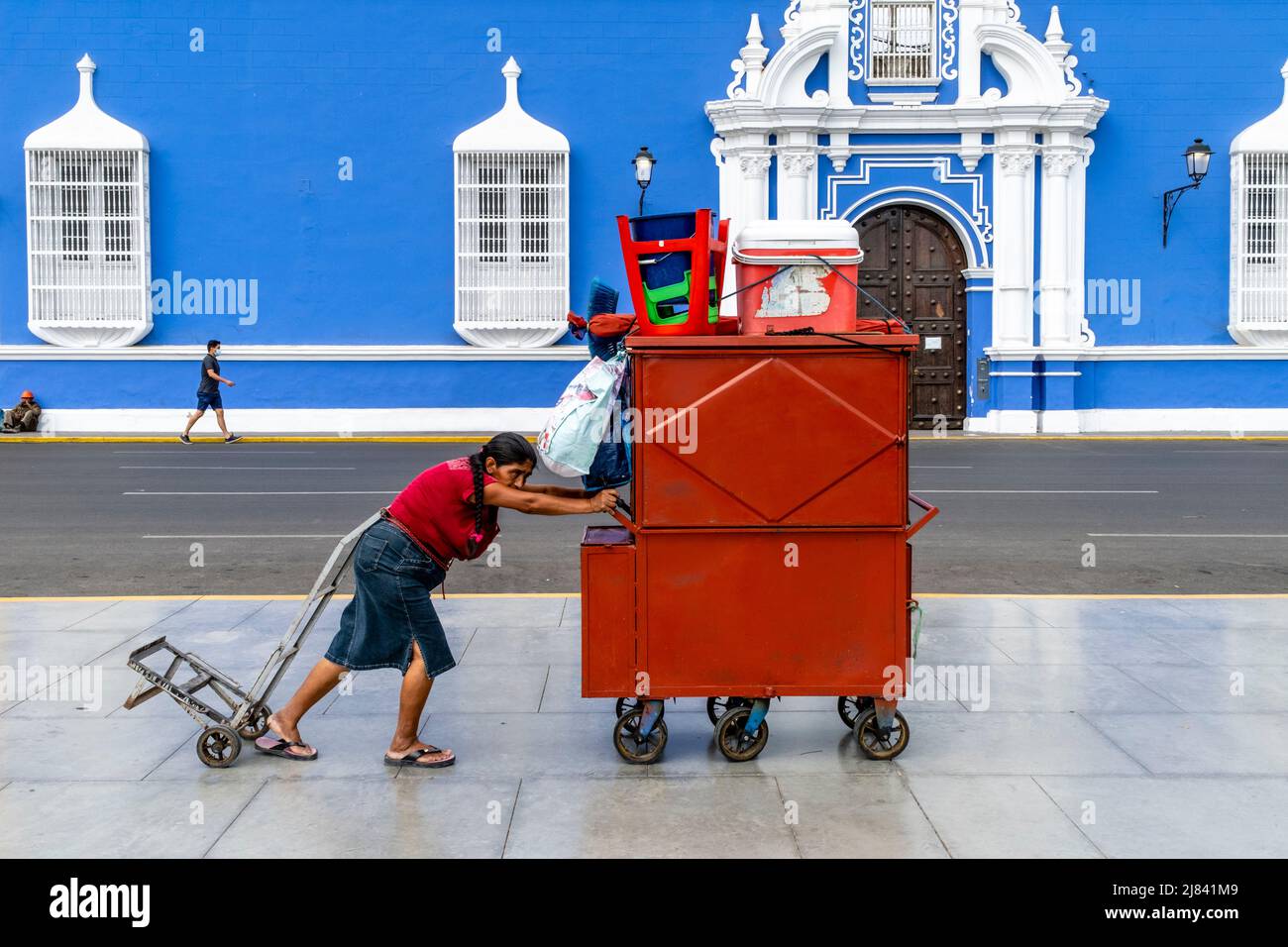 An Elderly Woman Pushes Her Mobile Food Kiosk Through The Plaza De Armas, Trujillo, La Libertad Region, Peru. Stock Photo