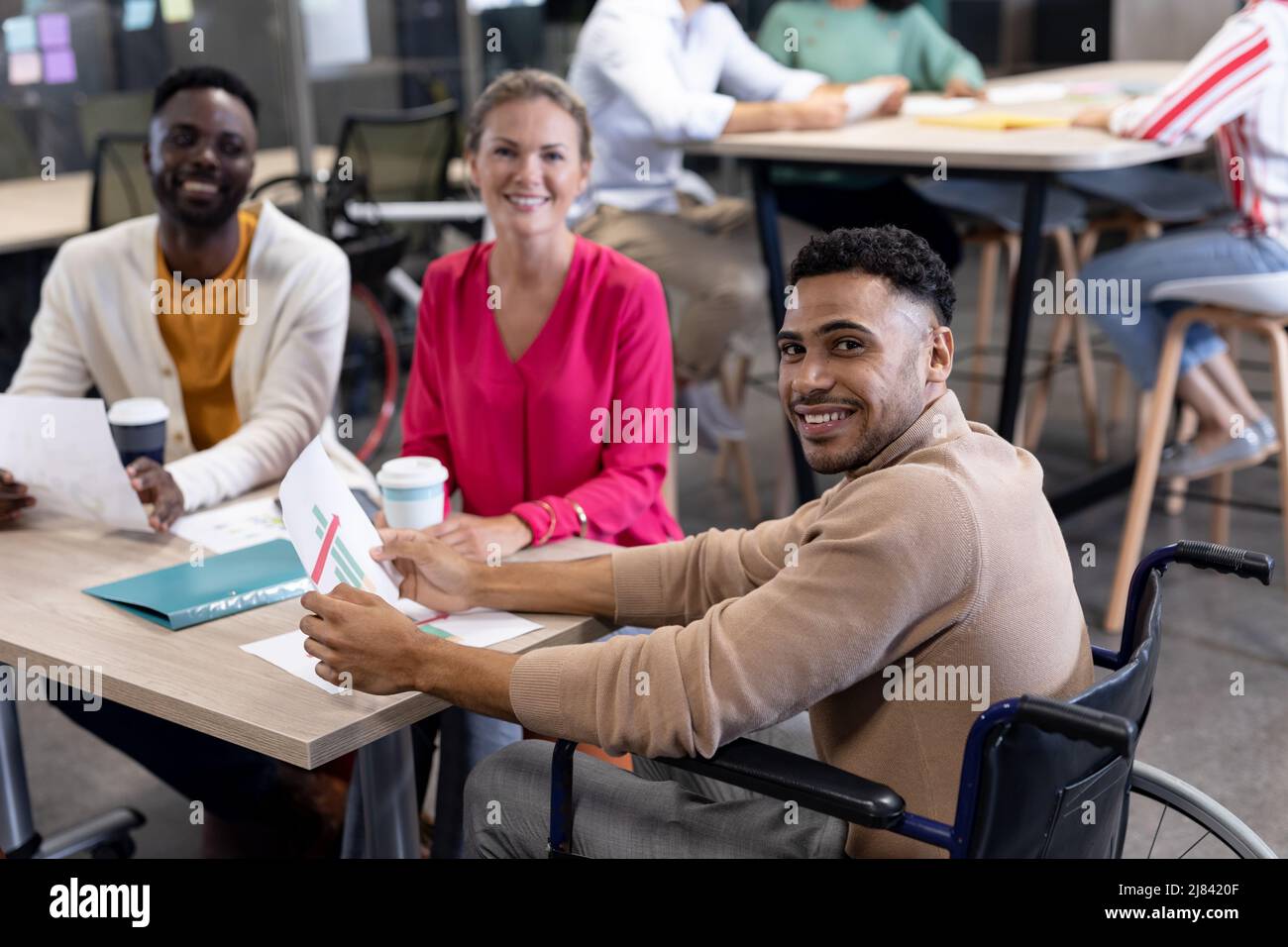 Portrait of hispanic disabled businessman with biracial colleagues in meeting at workplace Stock Photo