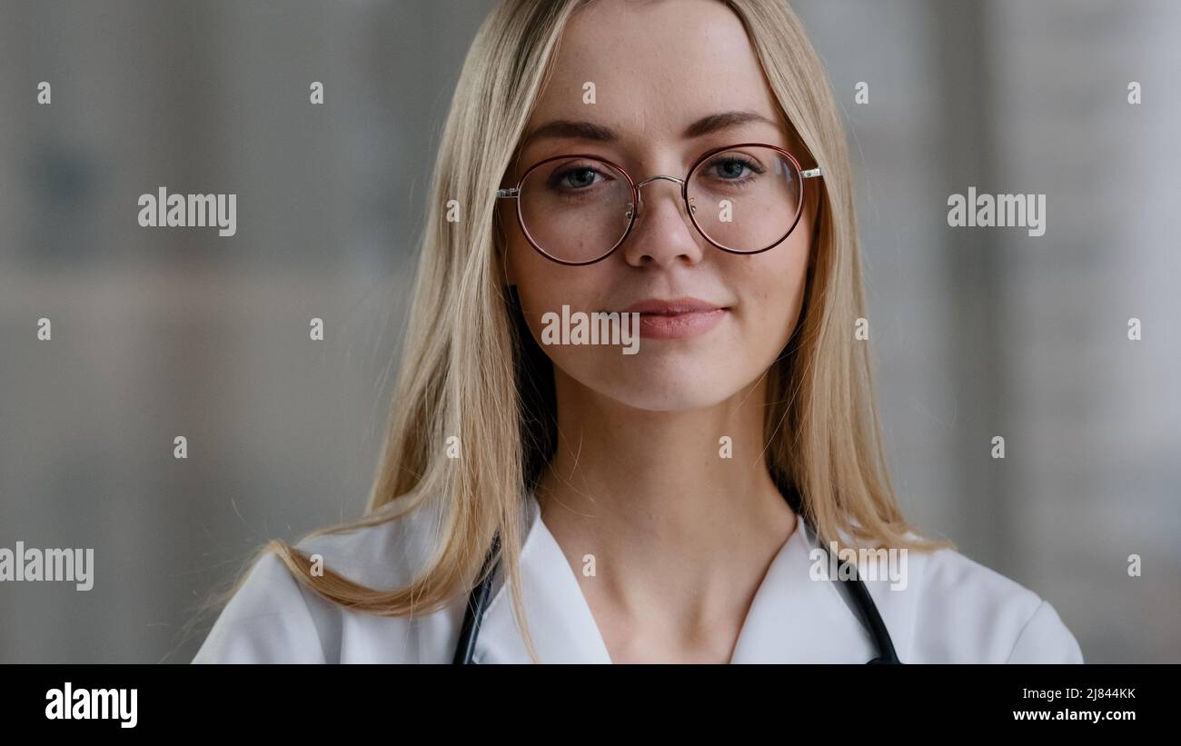 Caucasian female doctor wear eyeglasses make online video call in hospital clinic consult patient remote distant conversation. Medical assistant Stock Photo