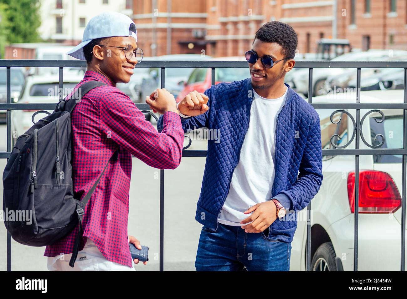 two stylish young friends hugging long-awaited meeting in street parking Stock Photo