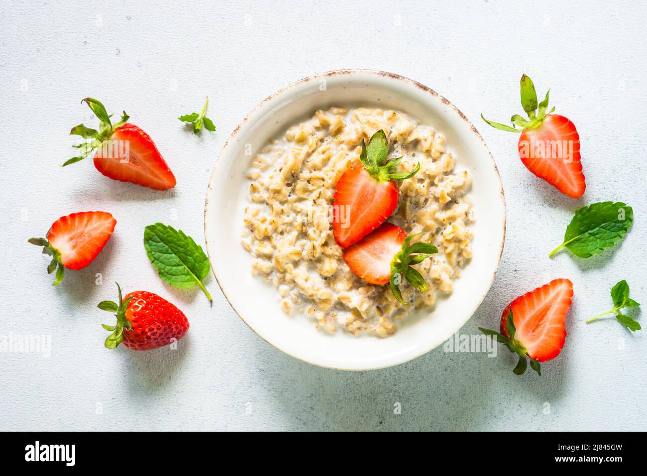 Oatmeal porridge with strawberry on white background. Stock Photo