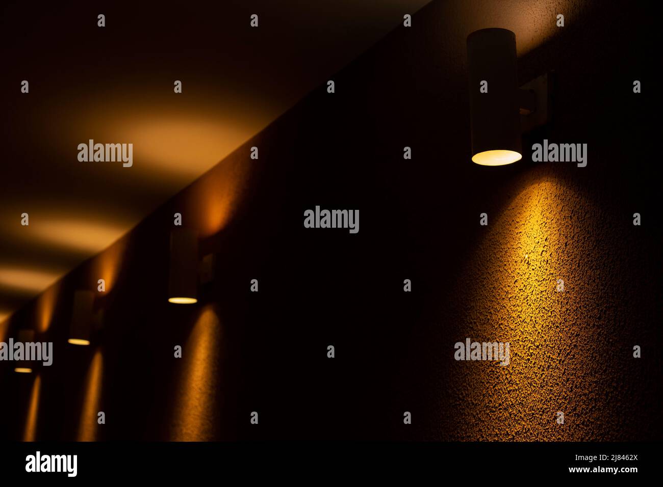 Goiânia, Goias, Brazil – May 11, 2022: A few spotlights illuminating a yellow textured concrete wall. Stock Photo