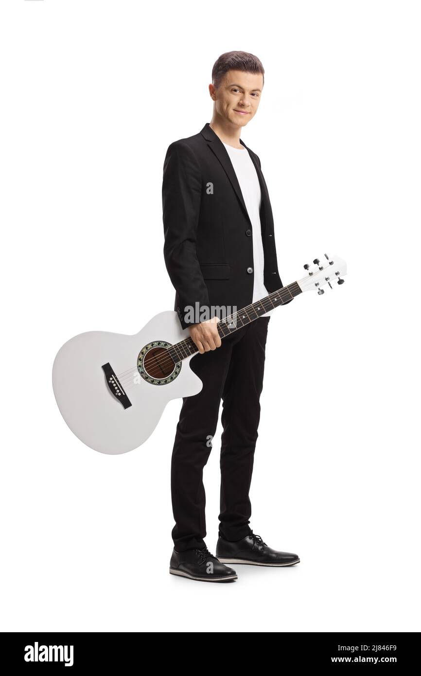 Elegant young man in a black suit holding an acoustic guitar and looking at camera isolated on white background Stock Photo