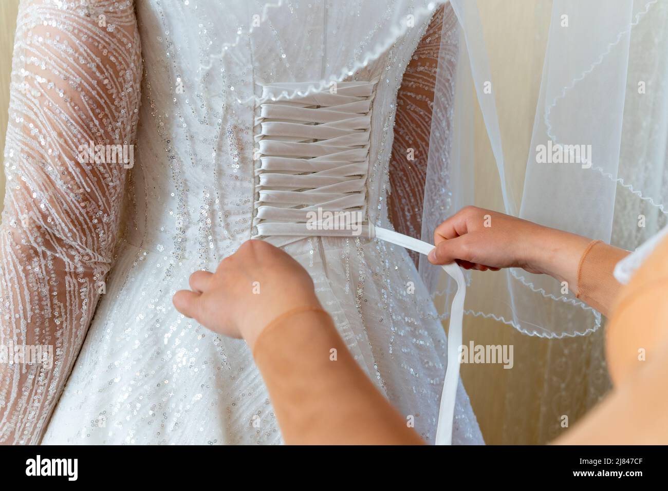 The bride helps to dress in a wedding dress. Lacing. Stock Photo