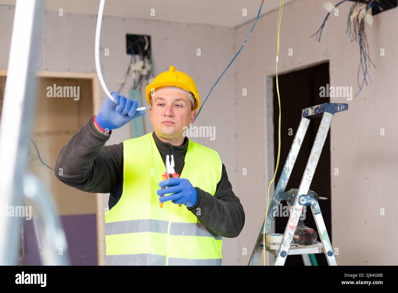 Electrician laying electric wires in building under construction Stock ...