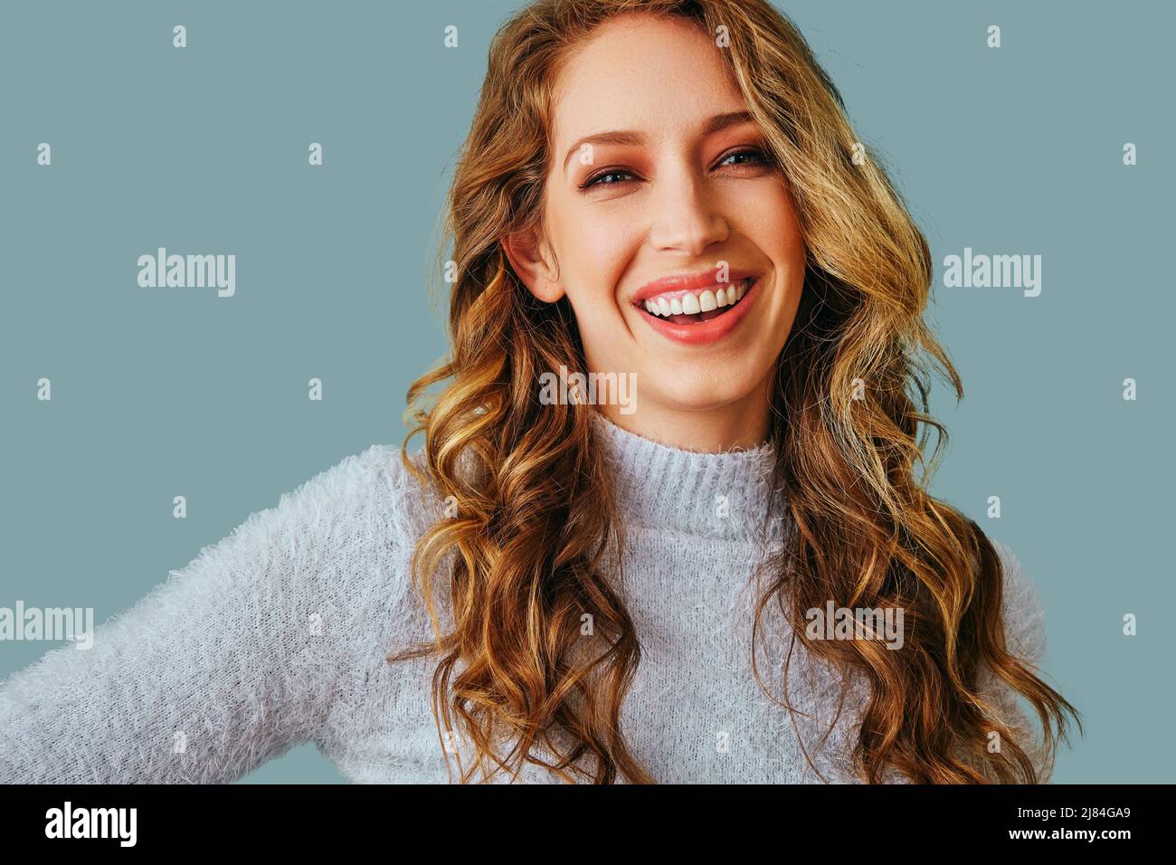 horizontal portrait of beautiful young adult smiling woman with long curly hair studio Stock Photo