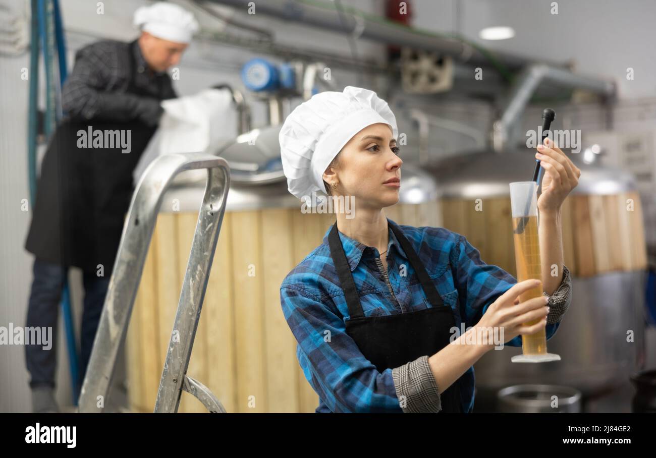 Female brewer using digital hydrometer for measuring beer density Stock