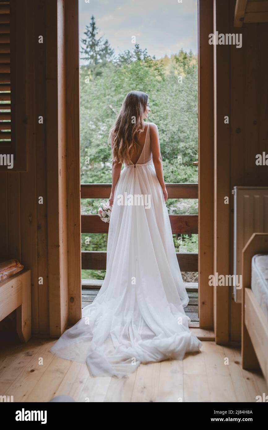 Back view of a bride standing waiting for her groom on the balcony ...