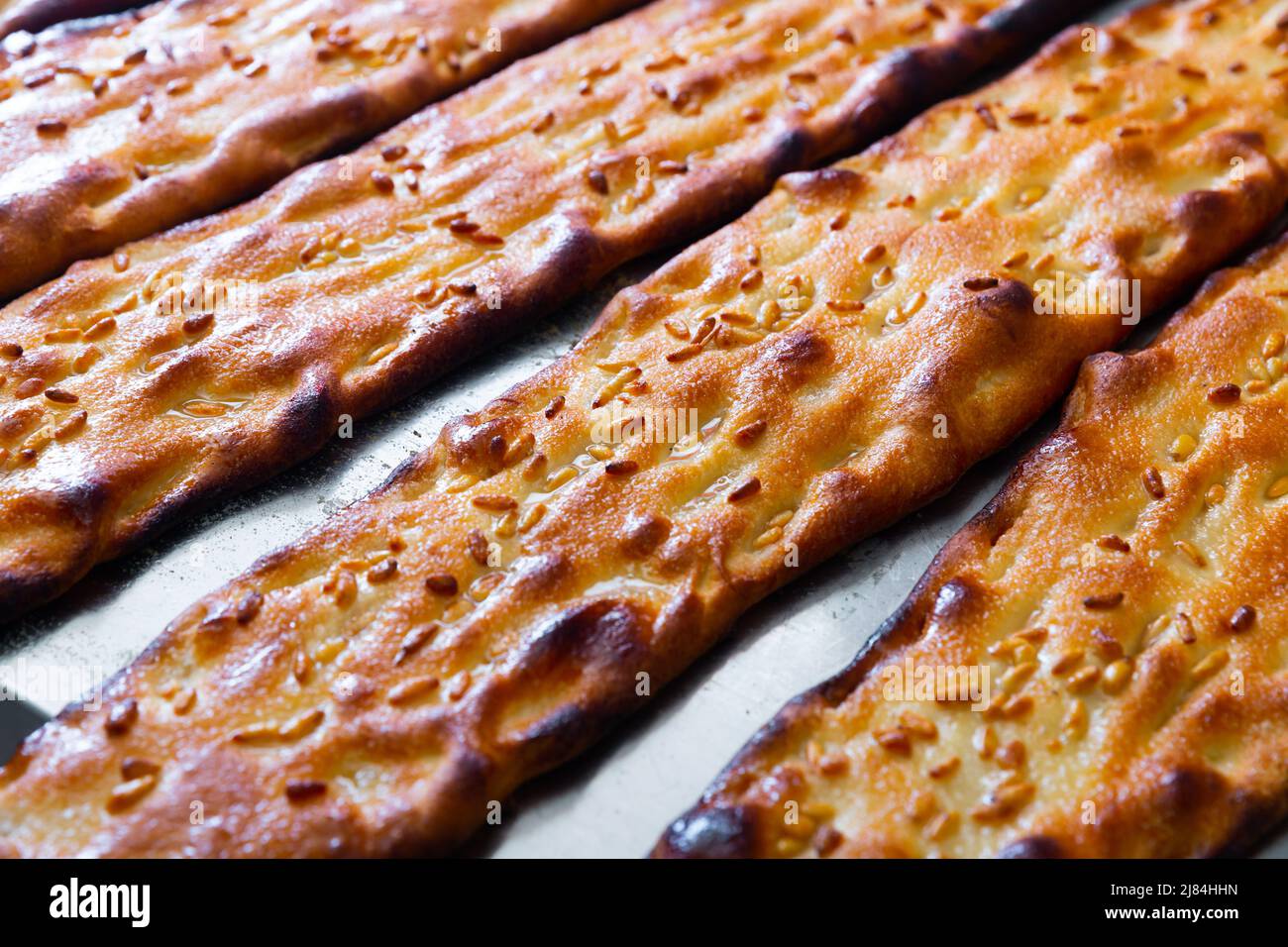 Closeup of freshly baked cocas with sesame on steel surface Stock Photo