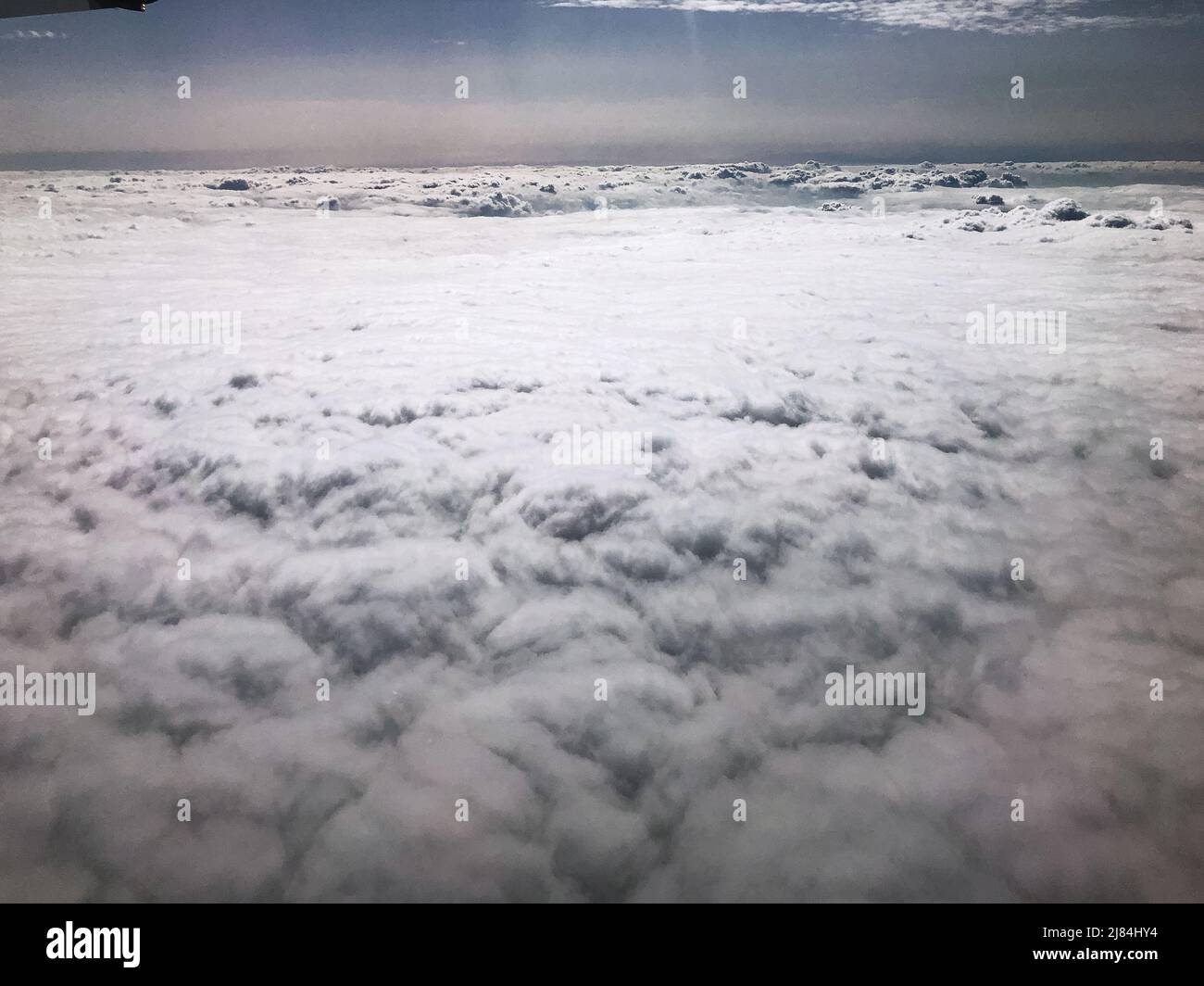 Flying above clouds and cloudscape from a plane window. Stock Photo
