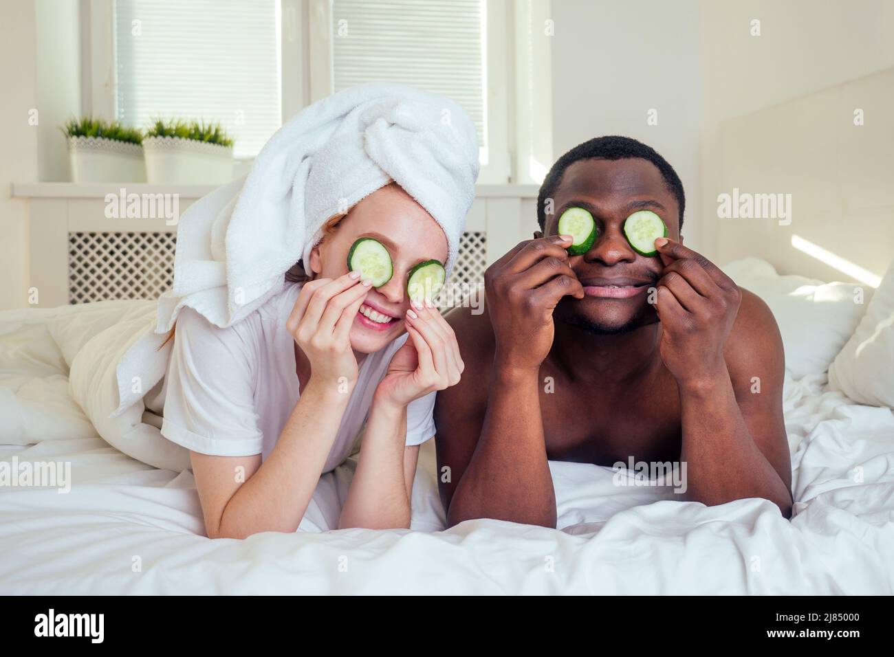 african american man and woman with wet hair wrapped on towel lying on