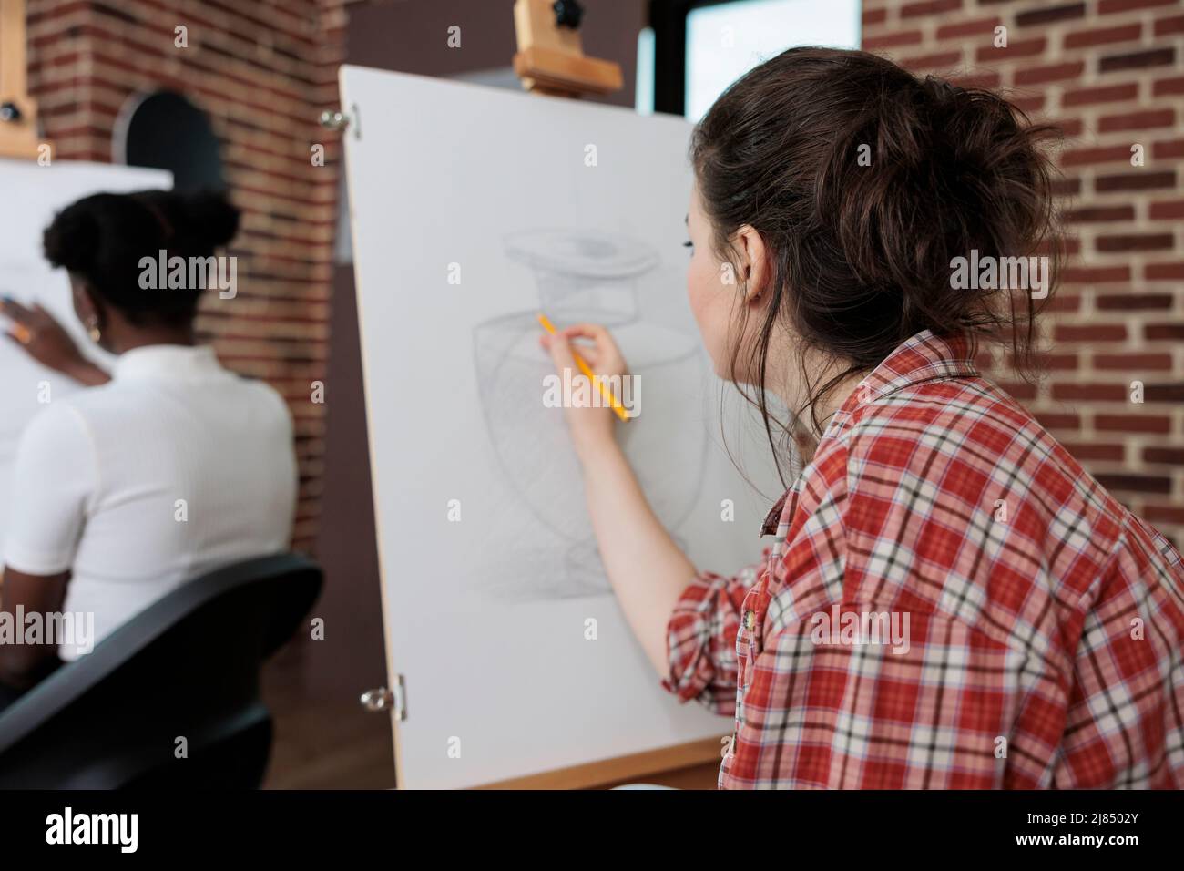 Painter woman drawing artistic vase on white canvas working at