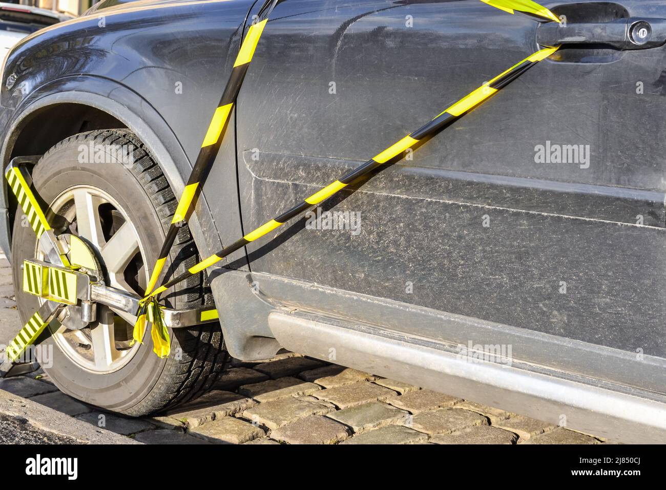 Car wheel is locked due illegal parking violation. Police equipment for blocking the car wheel of a parking rule violator. Stock Photo