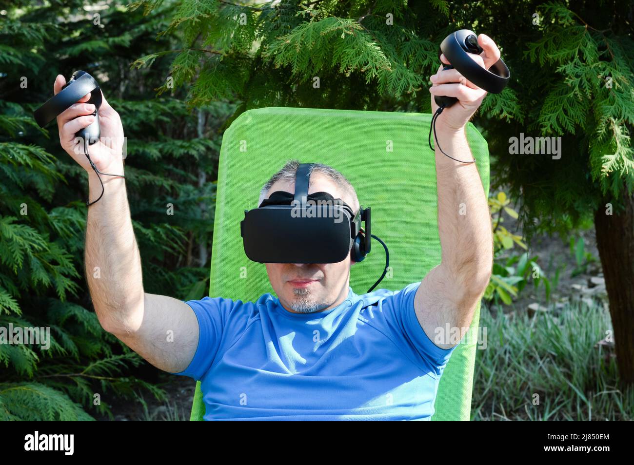 Happy man using a virtual reality headset and experiences a computer simulation of the virtual world and metaverse Stock Photo