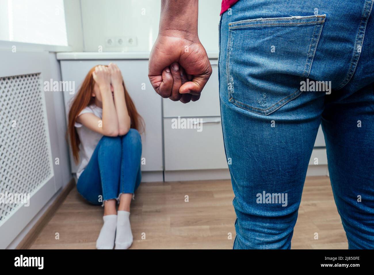 domestic violence. angry african american man hitting girl with bottle of alcohol at kitchen Stock Photo