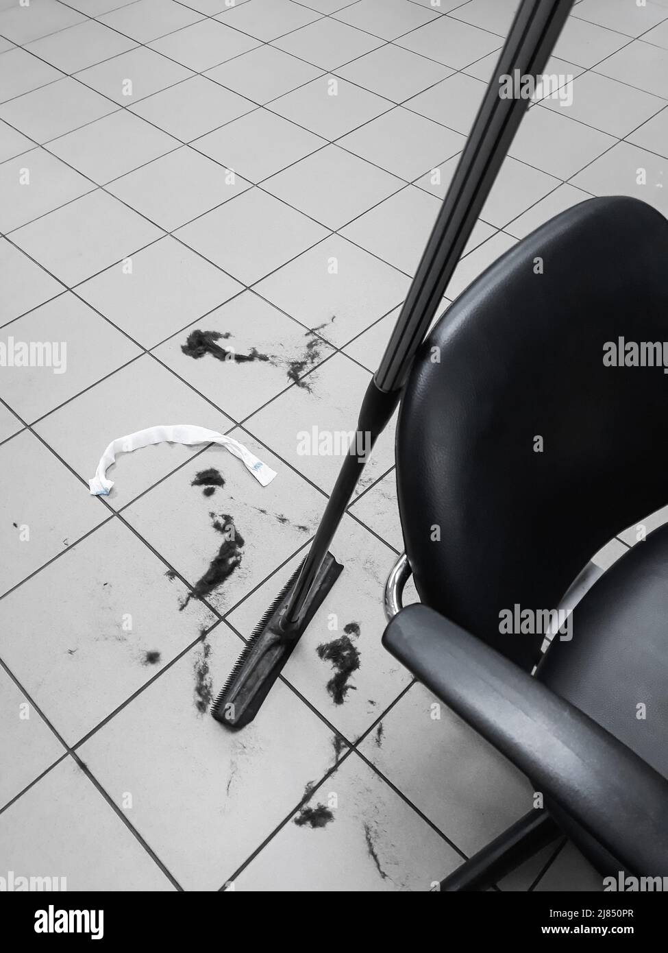 Rubber broom and hair on the floor after cutting hair in a hairdressers workspace in a barber