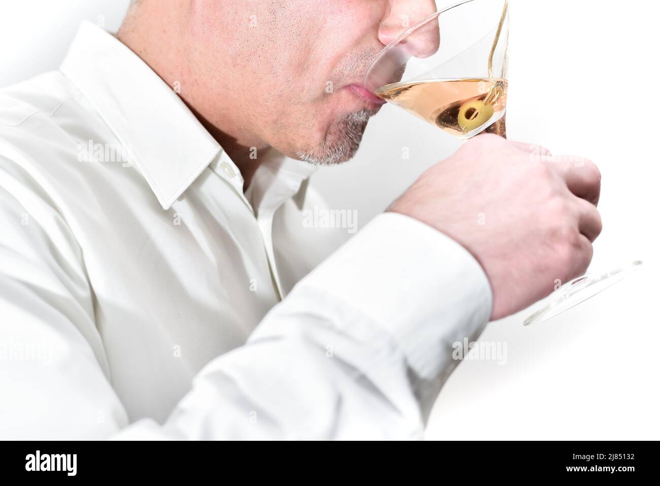Close-up of a man tasting and drinking martini cocktail with olives. Stock Photo