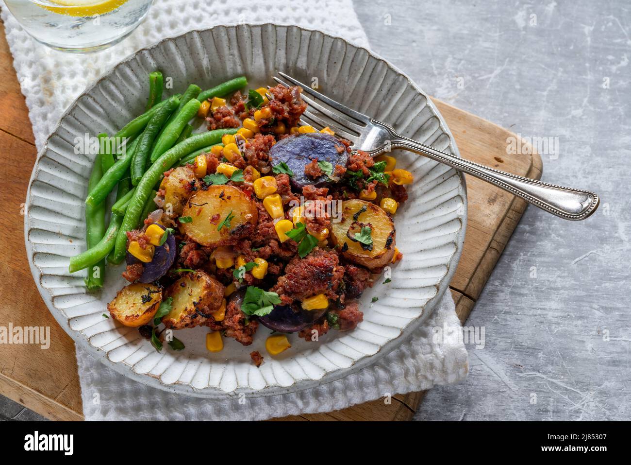 Corned beef, sweetcorn and potato hash with green beans Stock Photo