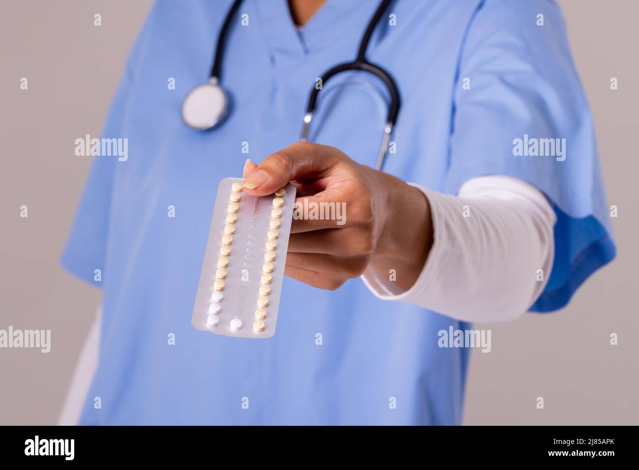 Midsection of african american mid adult female doctor with stethoscope holding blister pack Stock Photo