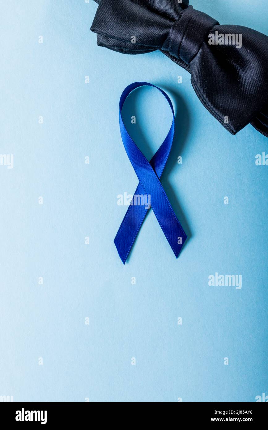 Directly above shot of blue prostate cancer awareness ribbon with black bowtie on blue background Stock Photo