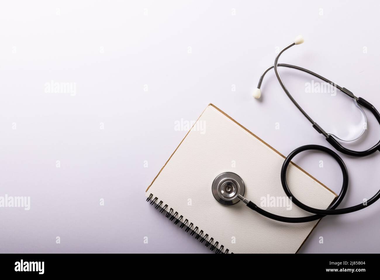 Directly above shot of blank spiral notebook with stethoscope on white background, copy space Stock Photo