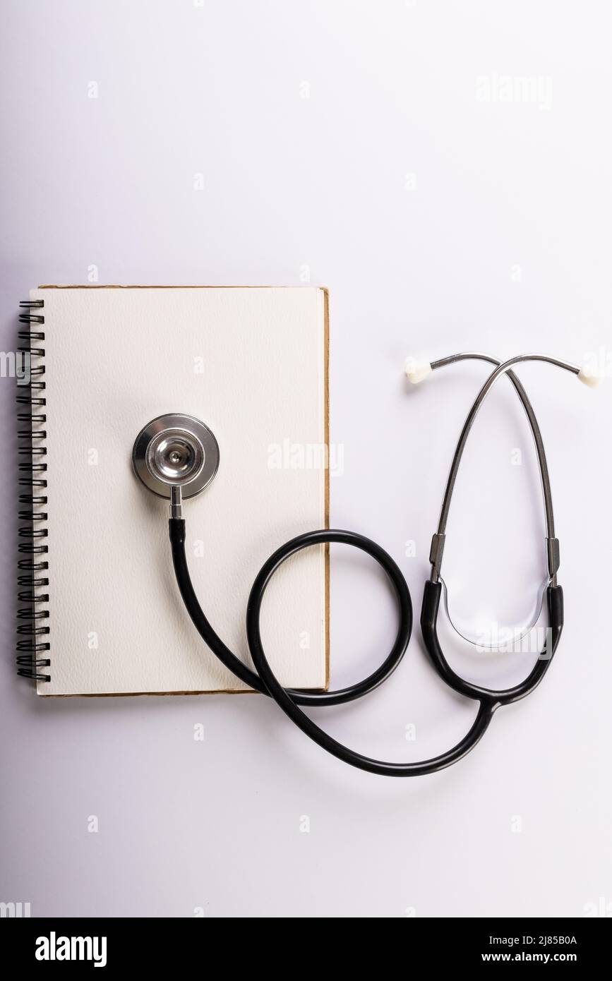 Directly above shot of blank spiral notebook and stethoscope on white background, copy space Stock Photo